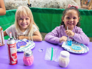 Two children decorate sugar cookies with icing and sprinkles at Irvine Park Railroad's Easter Eggstravaganza