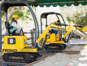 A child operates a stationary mini excavator at Irvine Park Railroad's Easter Eggstravaganza