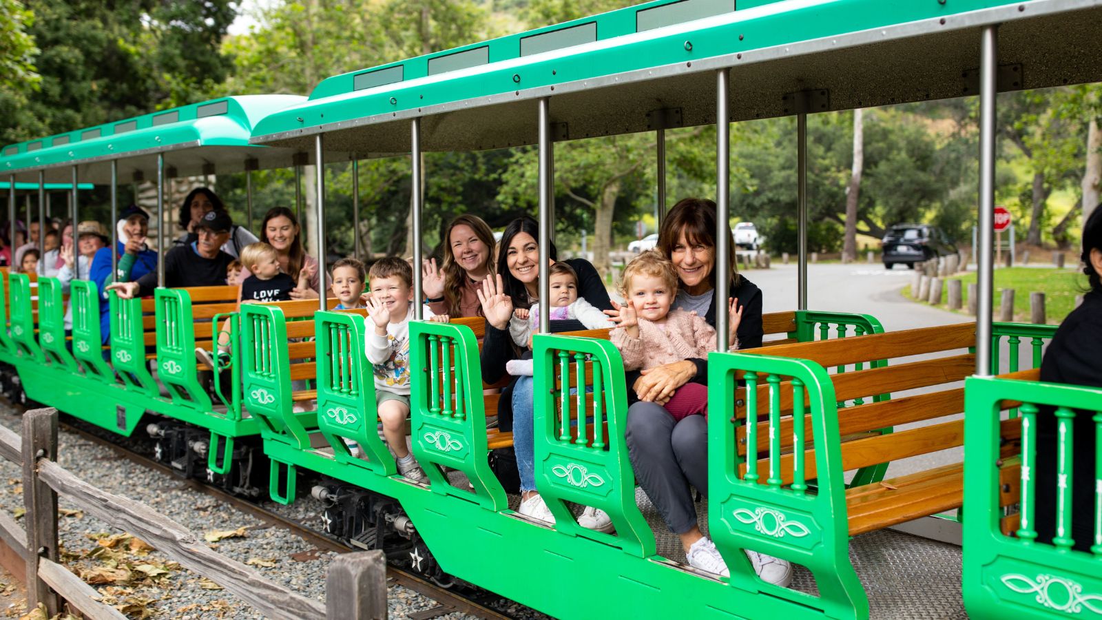 Children and adults wave as they ride the Irvine Park Railroad