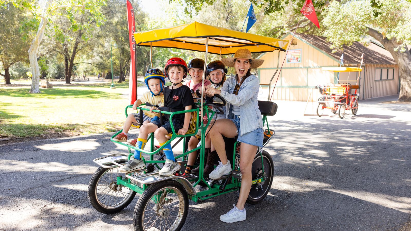 Four children and an adult are riding a single surrey rented from Irvine Park Rentals in Irvine Regional Park